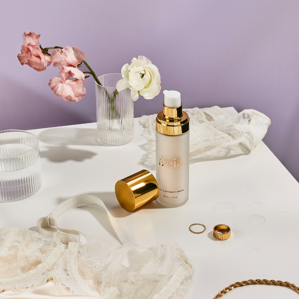beia body and intamacy serum on top of table with flower, rings, and lingerie