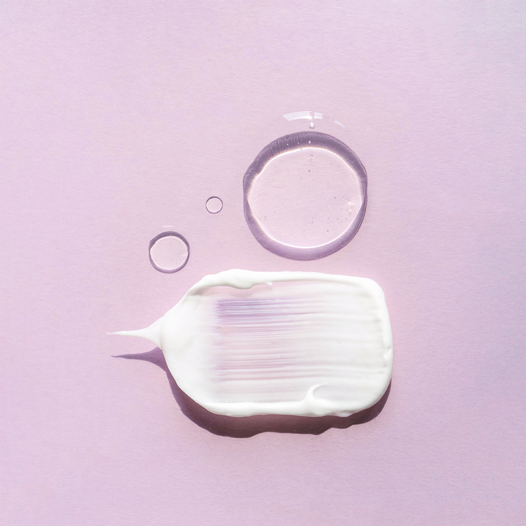 purple background with lotion and a drop of water