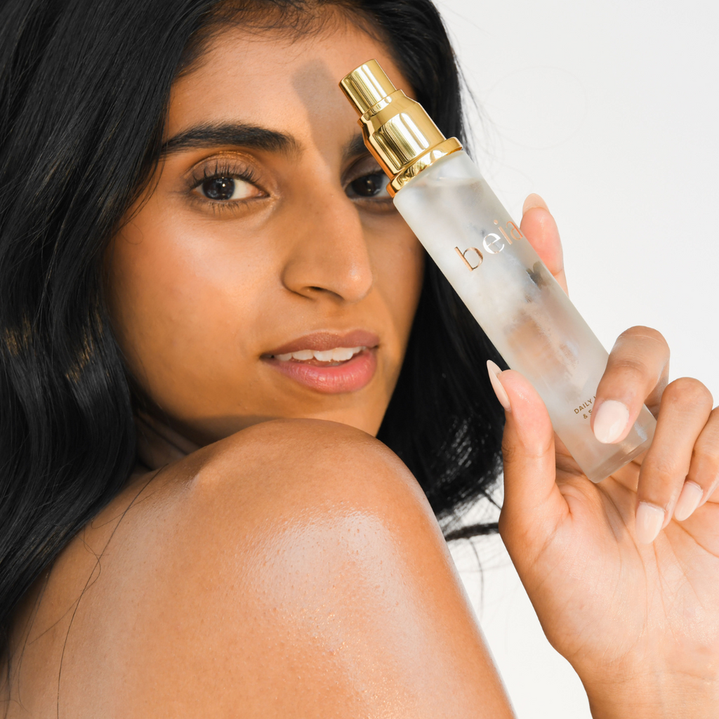 woman looking over shoulder while holding a bottle of hydrating mist