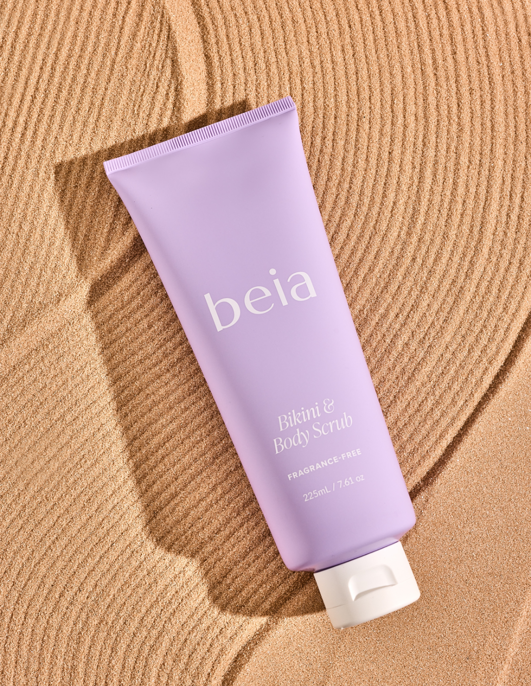 Purple tube of beia body scrub on a sand colored background