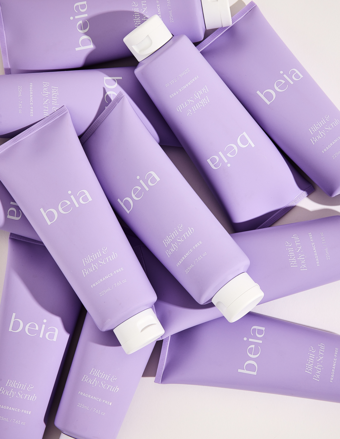 Many purple tubes of beia body scrub on a light gray background